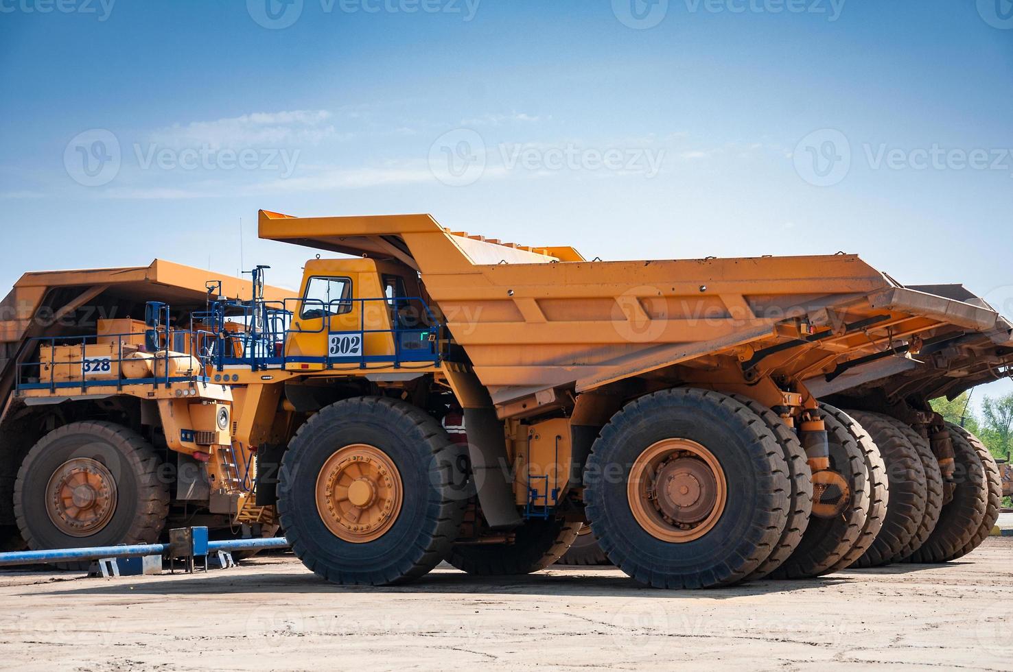 heavy yellow open cast mine dump trucks at repair station at sunny cloudless day photo