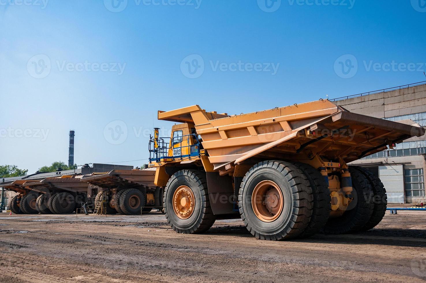 Quarry yellow dump truck drives alone industrial area at sunny day photo