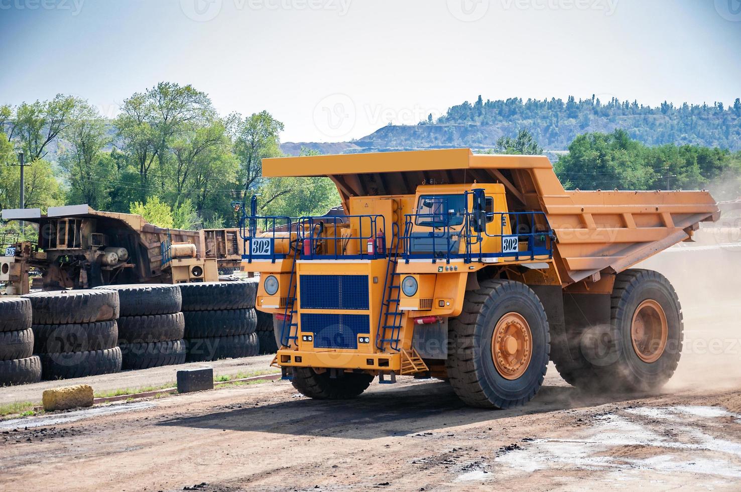 Quarry yellow dump truck drives alone industrial area at sunny day photo