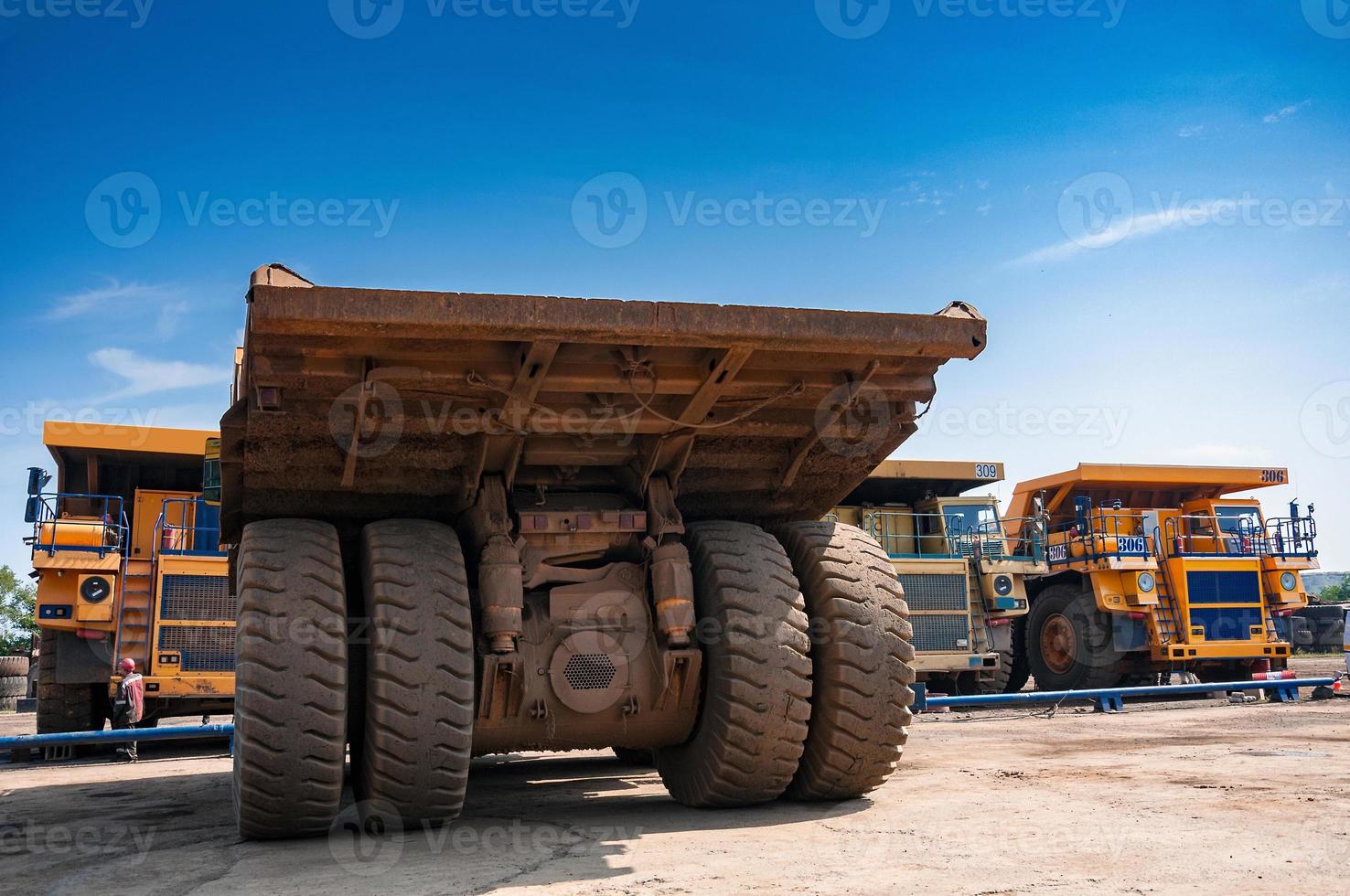 heavy yellow open cast mine dump trucks at repair station at sunny cloudless day photo