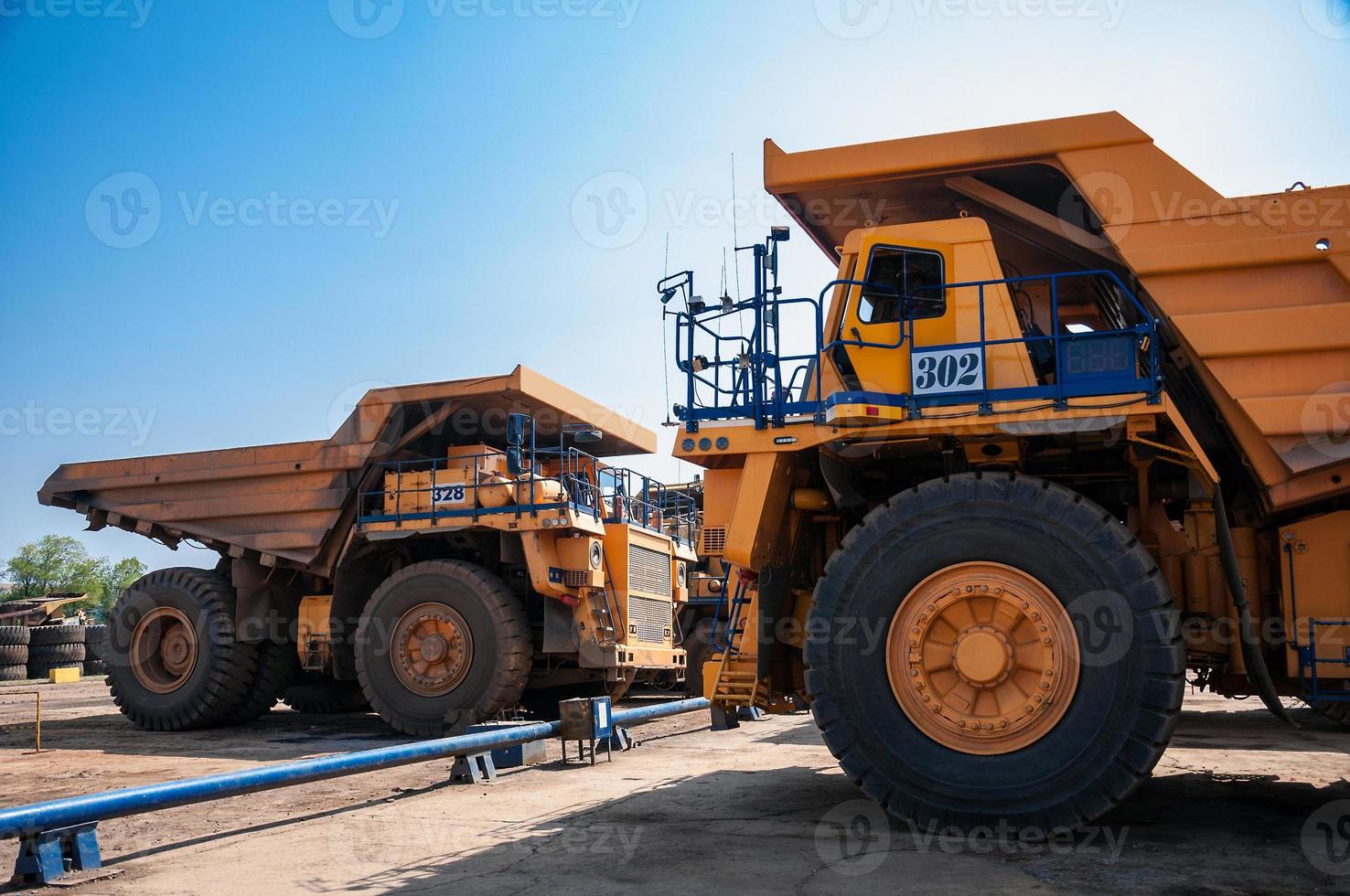 heavy yellow open cast mine dump trucks at repair station at sunny cloudless day photo