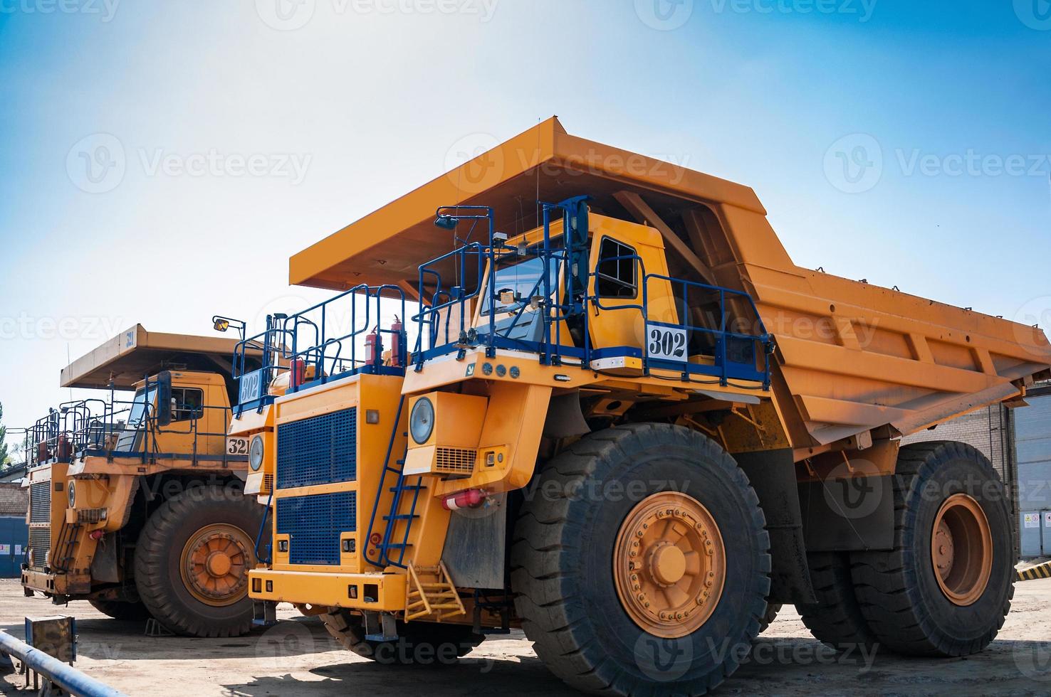 heavy yellow open cast mine dump trucks at repair station at sunny cloudless day photo