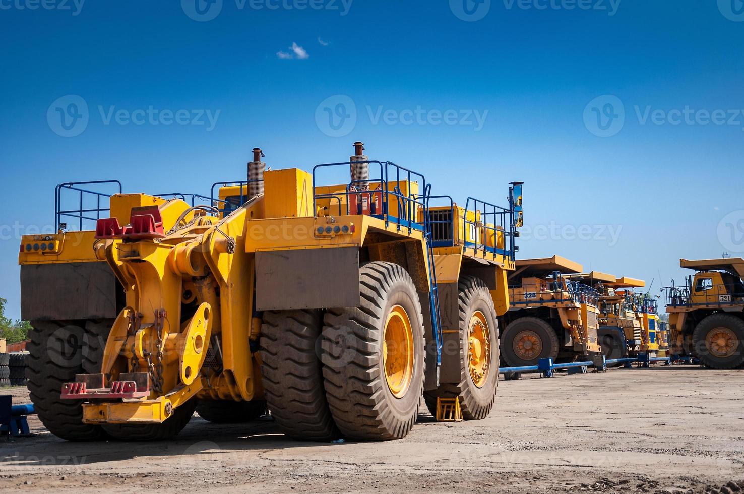 Heavy yellow quarry tractor at repair station at sunny cloudless day photo