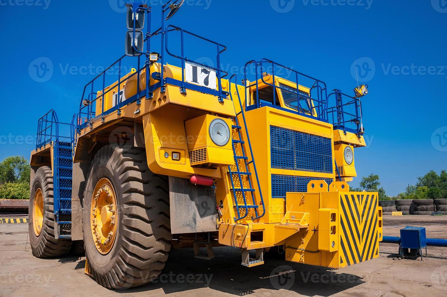 Heavy yellow quarry tractor at repair station at sunny cloudless day photo