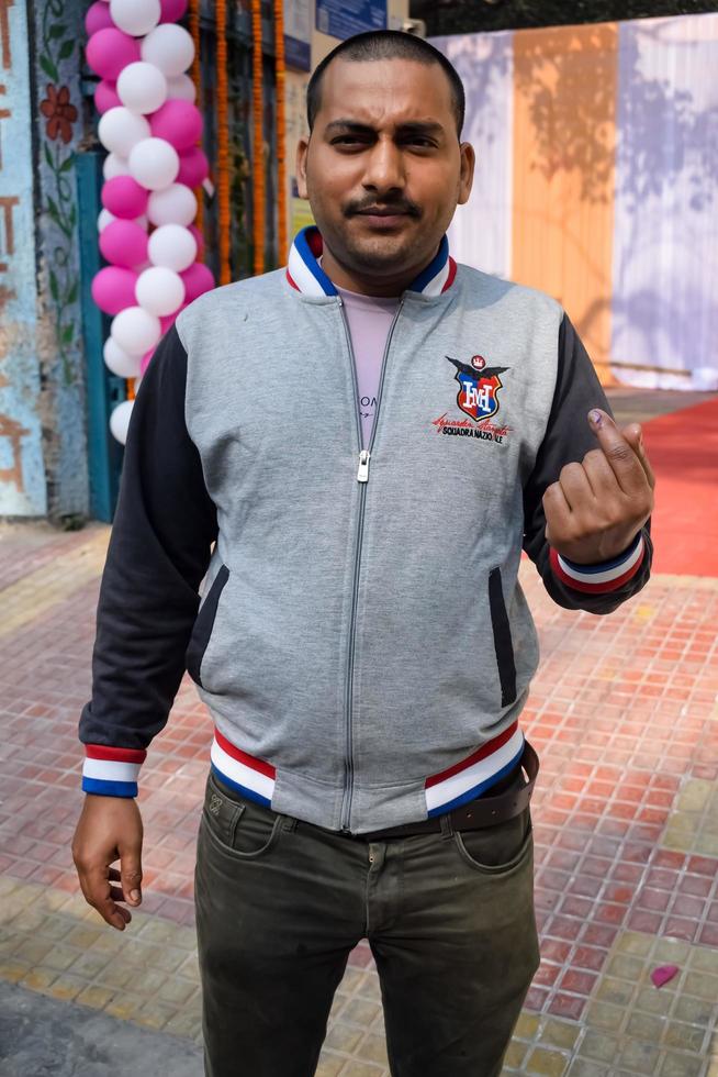 New Delhi, India - March 04 2023 - Unidentified people showing their ink-marked fingers after casting votes in front of polling booth of east Delhi area for MCD local body Elections 2022 photo