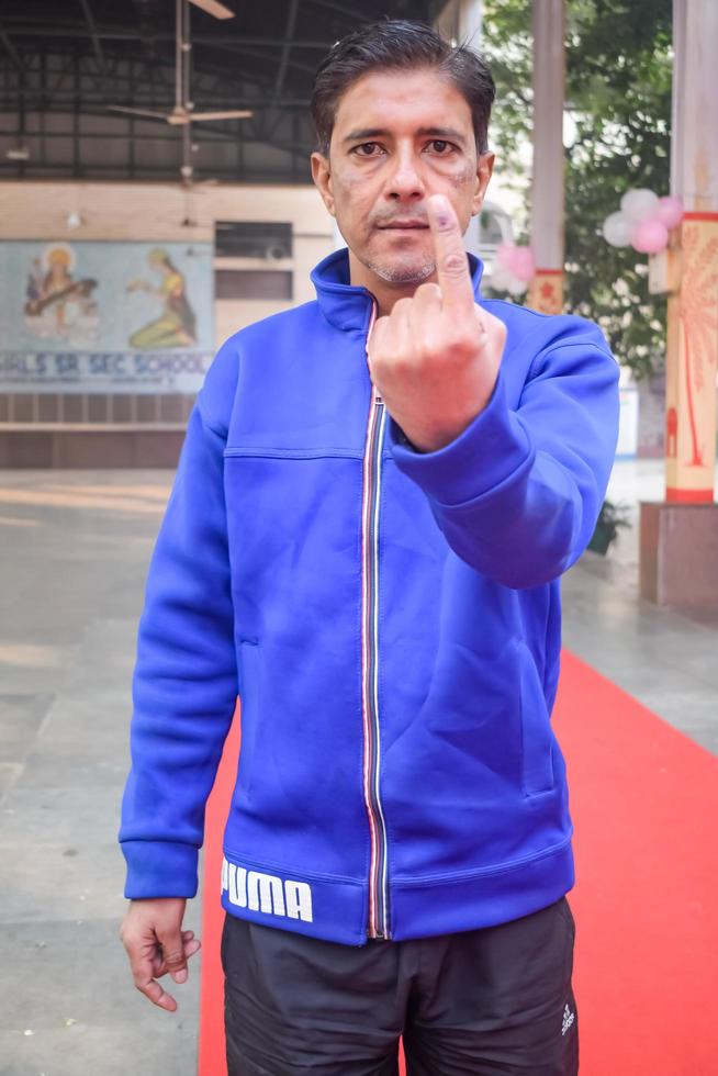 New Delhi, India - March 04 2023 - Unidentified people showing their ink-marked fingers after casting votes in front of polling booth of east Delhi area for MCD local body Elections 2022 photo