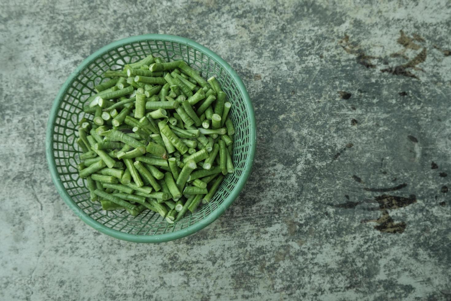 long bean pieces in a green plastic container on a gray background. top angle. photo