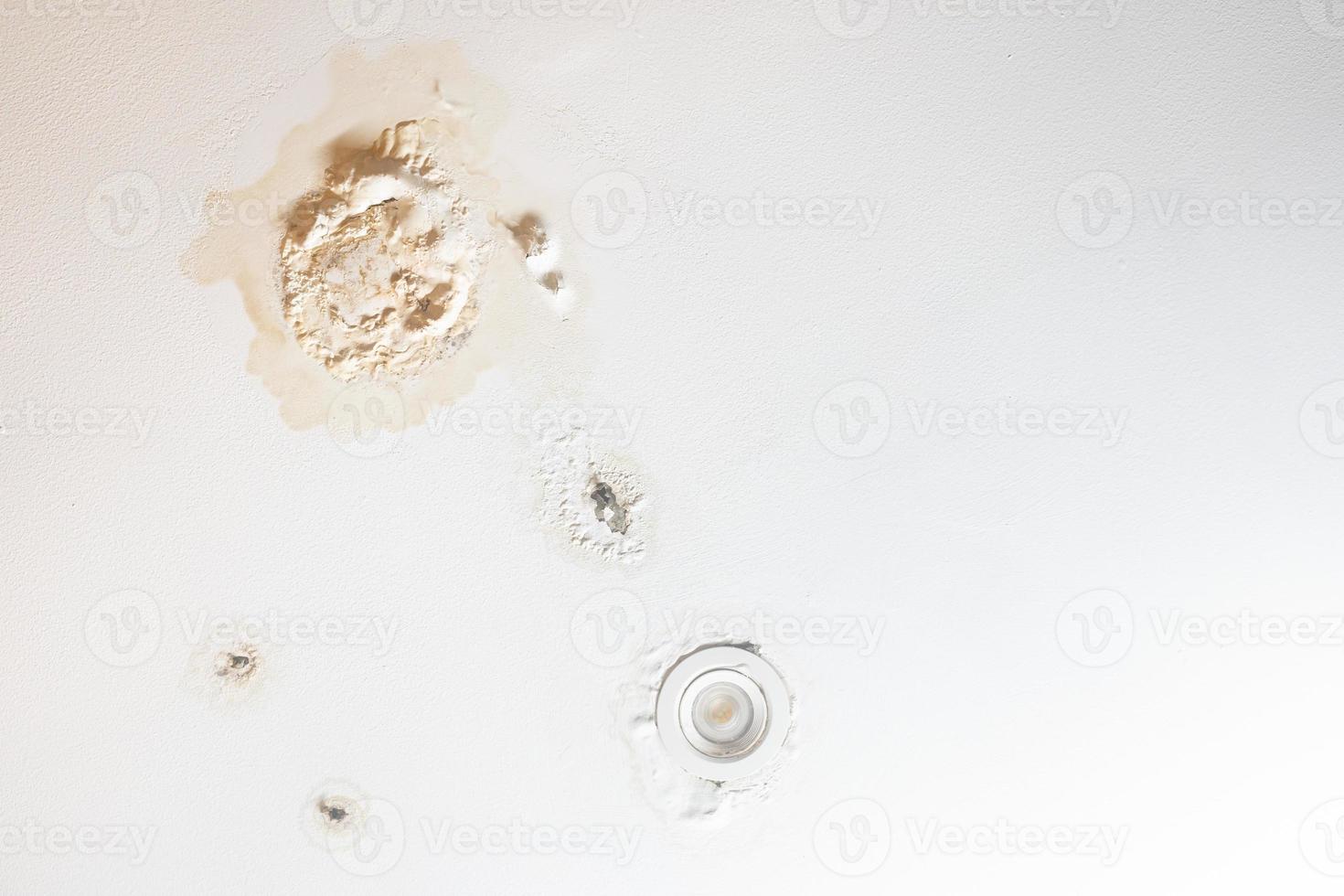 Water damaged ceiling in a house. Water damage building interior. Ceiling house broken. old peeling decay white gypsum board ceiling in house damage by water. photo