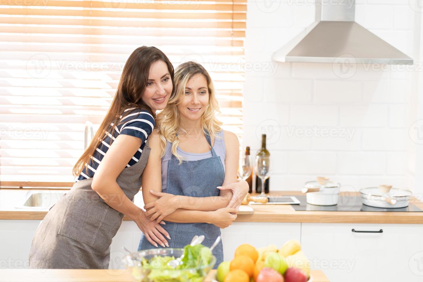 Happy LGBT lesbian couple dancing while cooking together at home. Girl dancing and turning, enjoying togetherness at background neon sign with word Together. Concept lgbt couple. photo