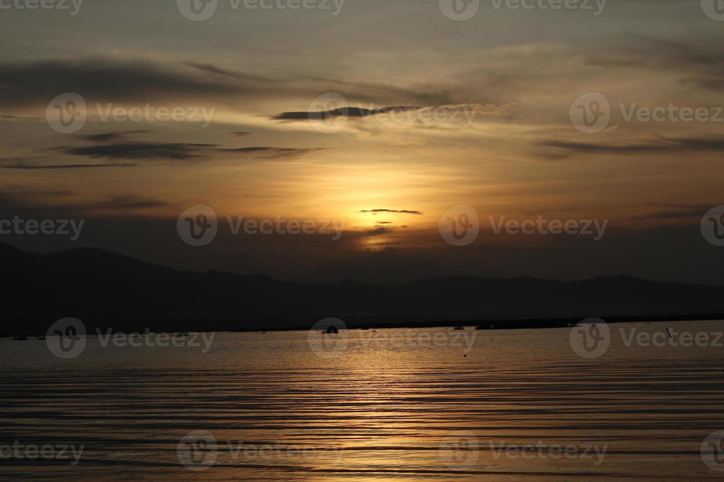 A sunset over the water with mountains in the background photo