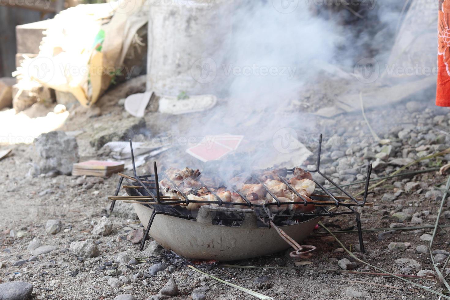 Chicken satay being grilled over coals photo