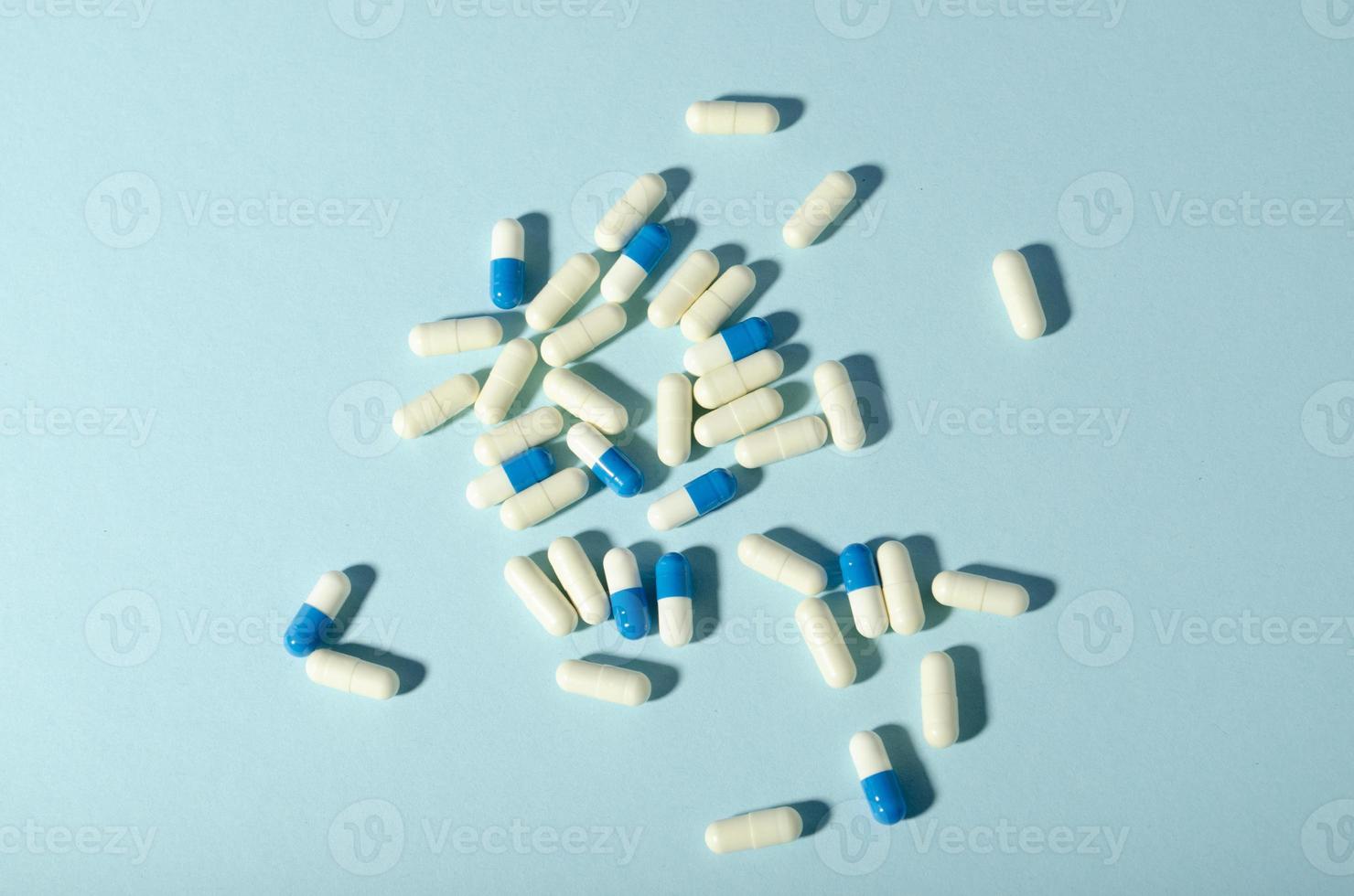 Randomly scattered pills. White and blue pills on blue background. photo