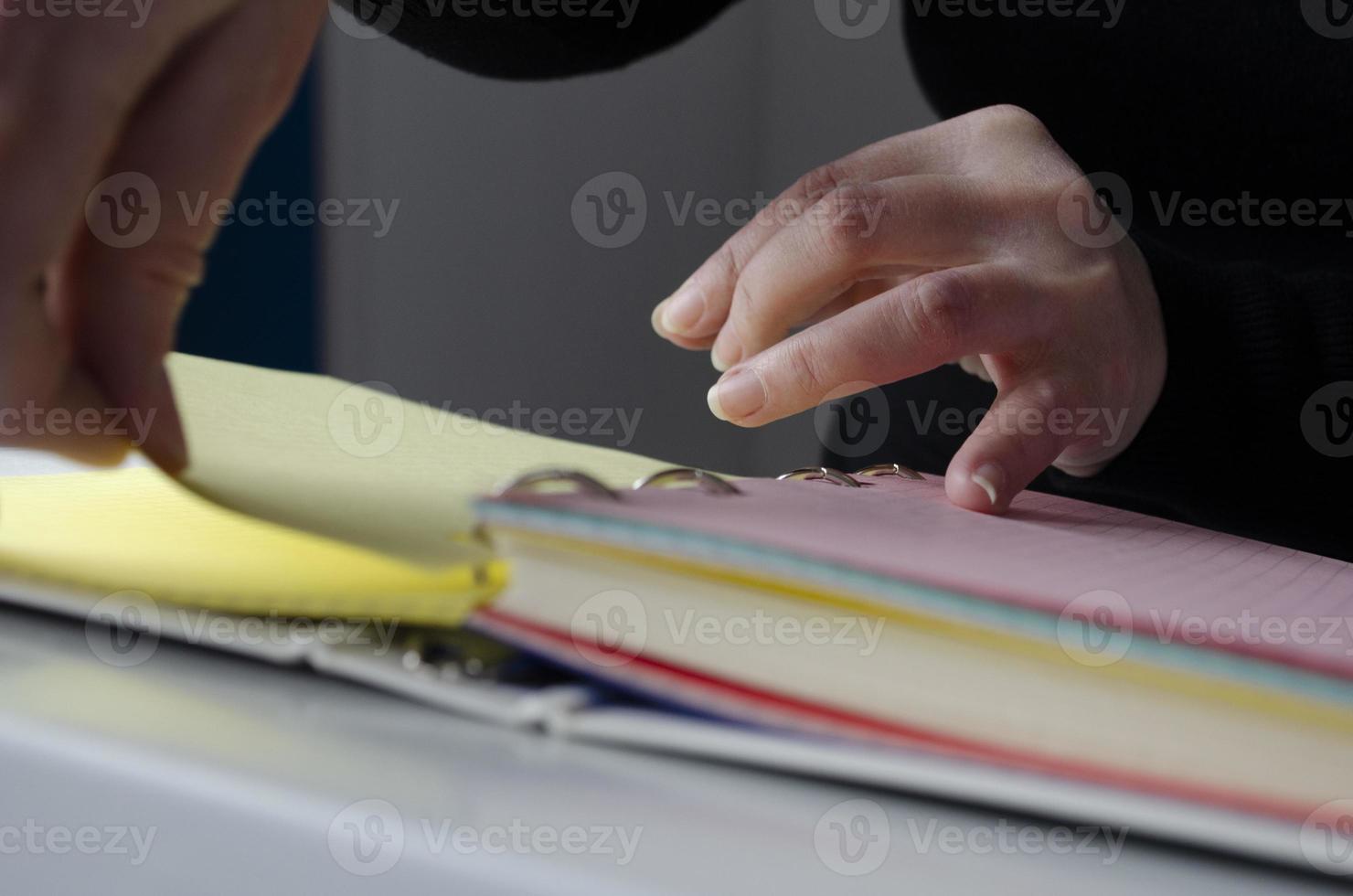 A person reading books near the window. Hands turns over book page. photo