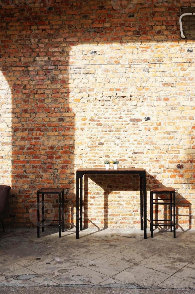 A brick wall with a table and two chairs in front of it photo
