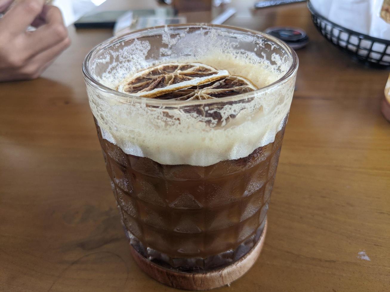 Arabica coffee ice with dried lemon slice with cream foaming. The photo is suitable to use for coffee shop background, menu poster and coffee content media.