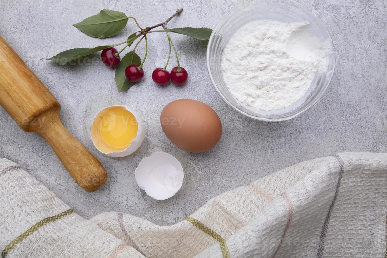 Ingredients baking flour eggs rolling pin berries kitchen textiles on gray background. Cookie pie or cake recipe mockup. Background preparation for culinary baking. photo