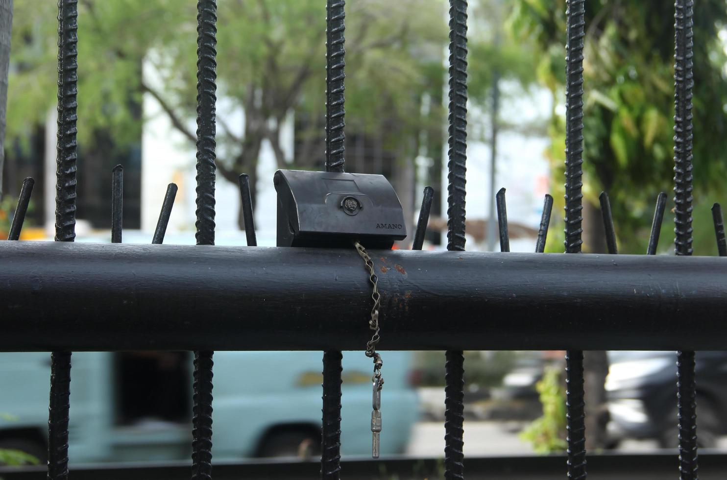 Jakarta, Indonesia - April 10th, 2023 - Small object on black fence with public road outdoor background, with metal iron chain lock. photo
