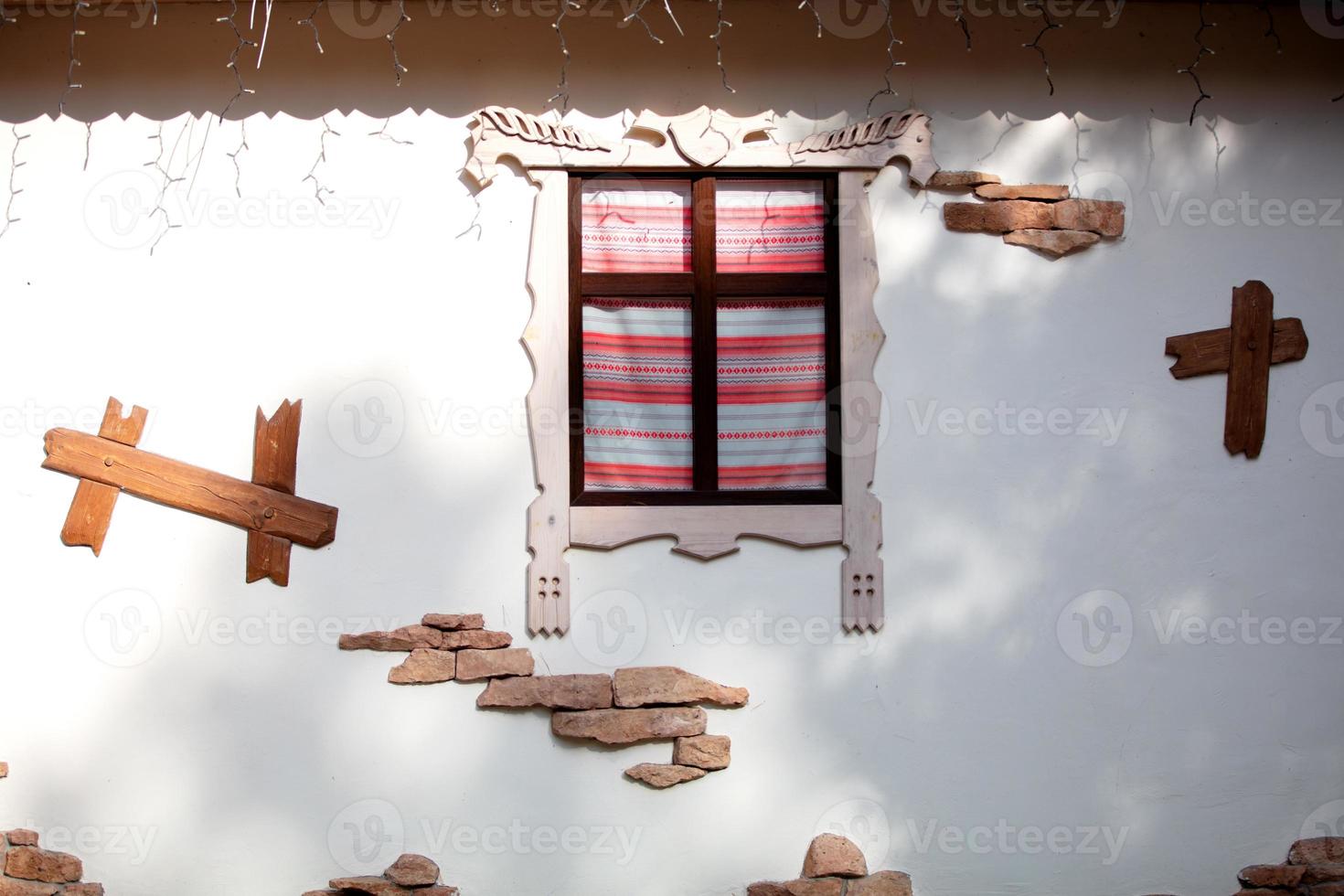 A fragment of a Ukrainian village house. Ethnic wall with a window. photo