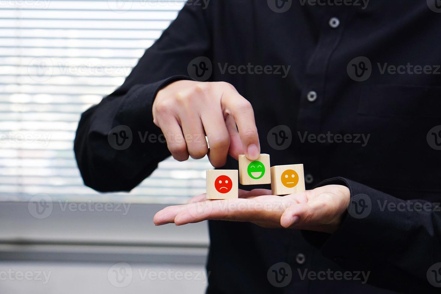 Businessman holding a wooden block cube with satisfaction icon symbol. Emotion, mindset and satisfaction concept. photo