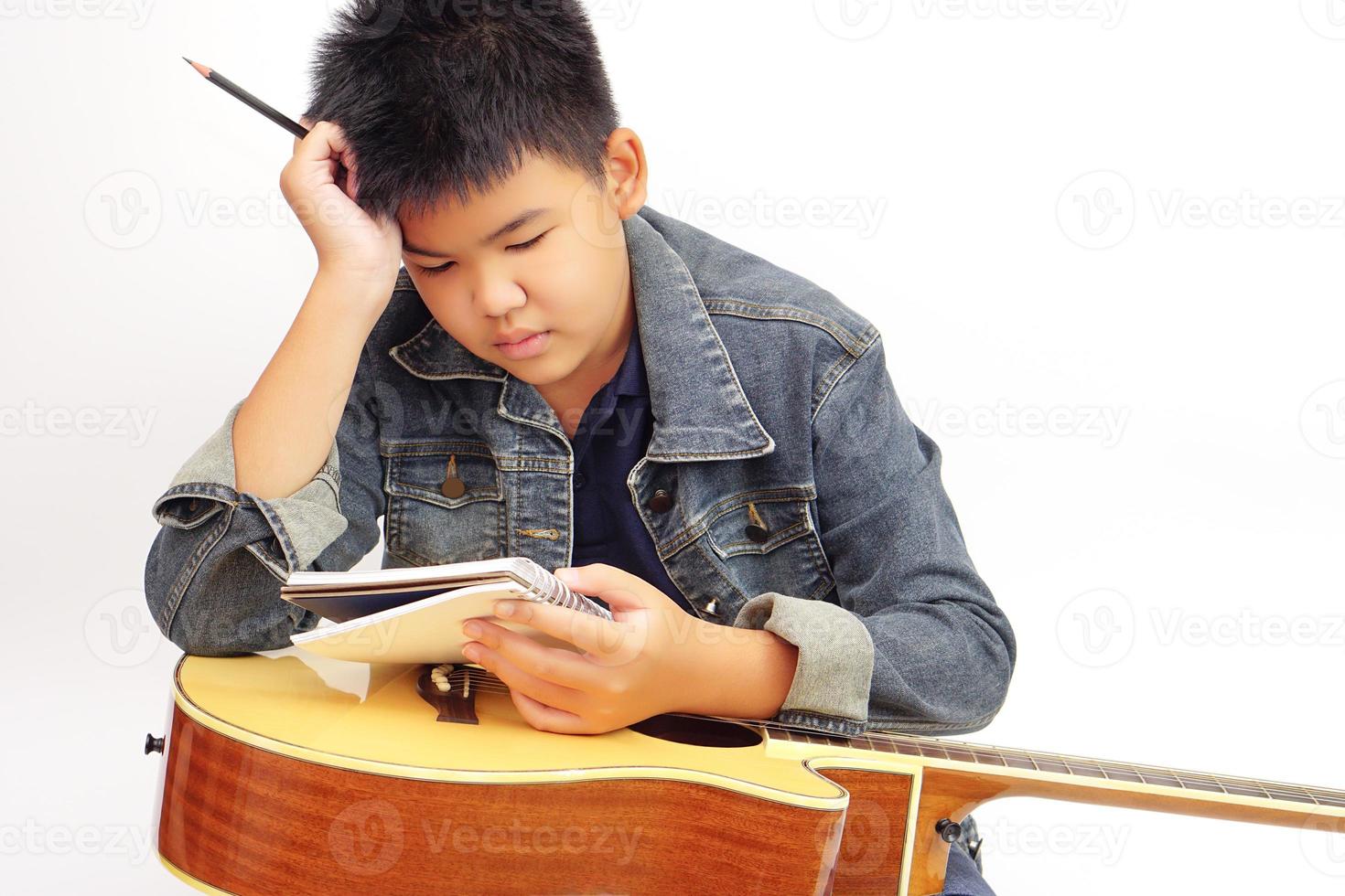 niño o adolescente pensando con tener un lápiz, cuaderno para tomando notas y acústico guitarra. aprendiendo, práctica y relajarse concepto. foto