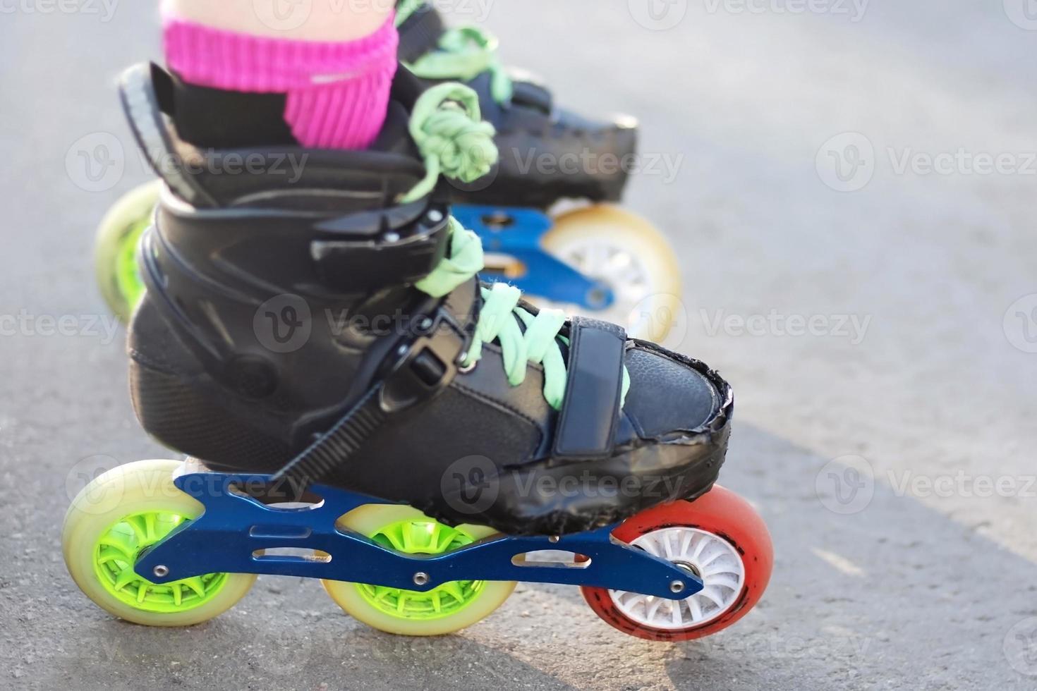 female caucasian roller skater legs in colorful skate footwear for inline and slalom skating standing on asphalt photo