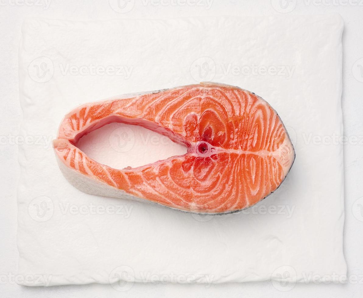 Raw piece of salmon on a white board, top view photo
