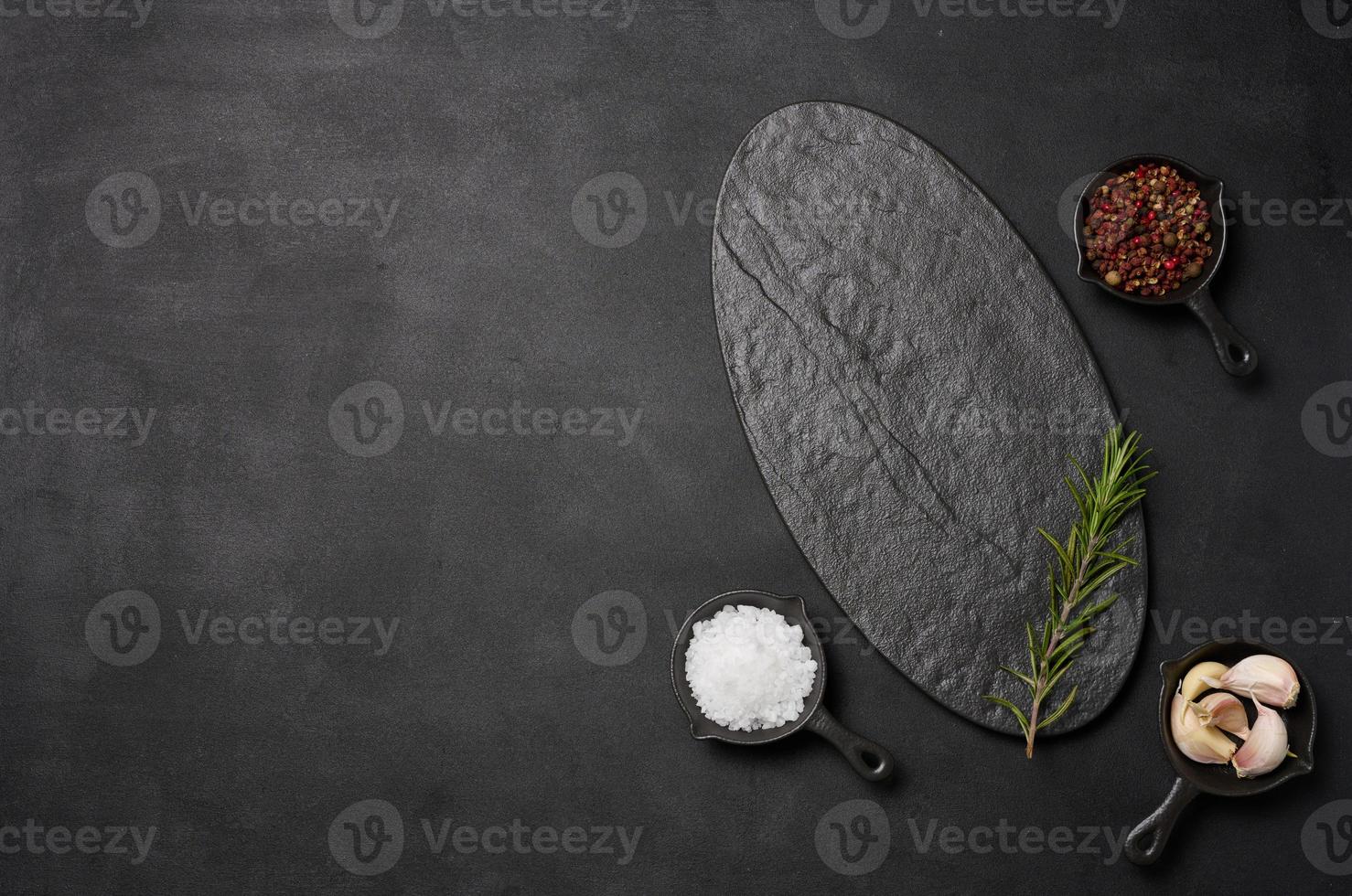 Empty black board and spices on black background, top view photo