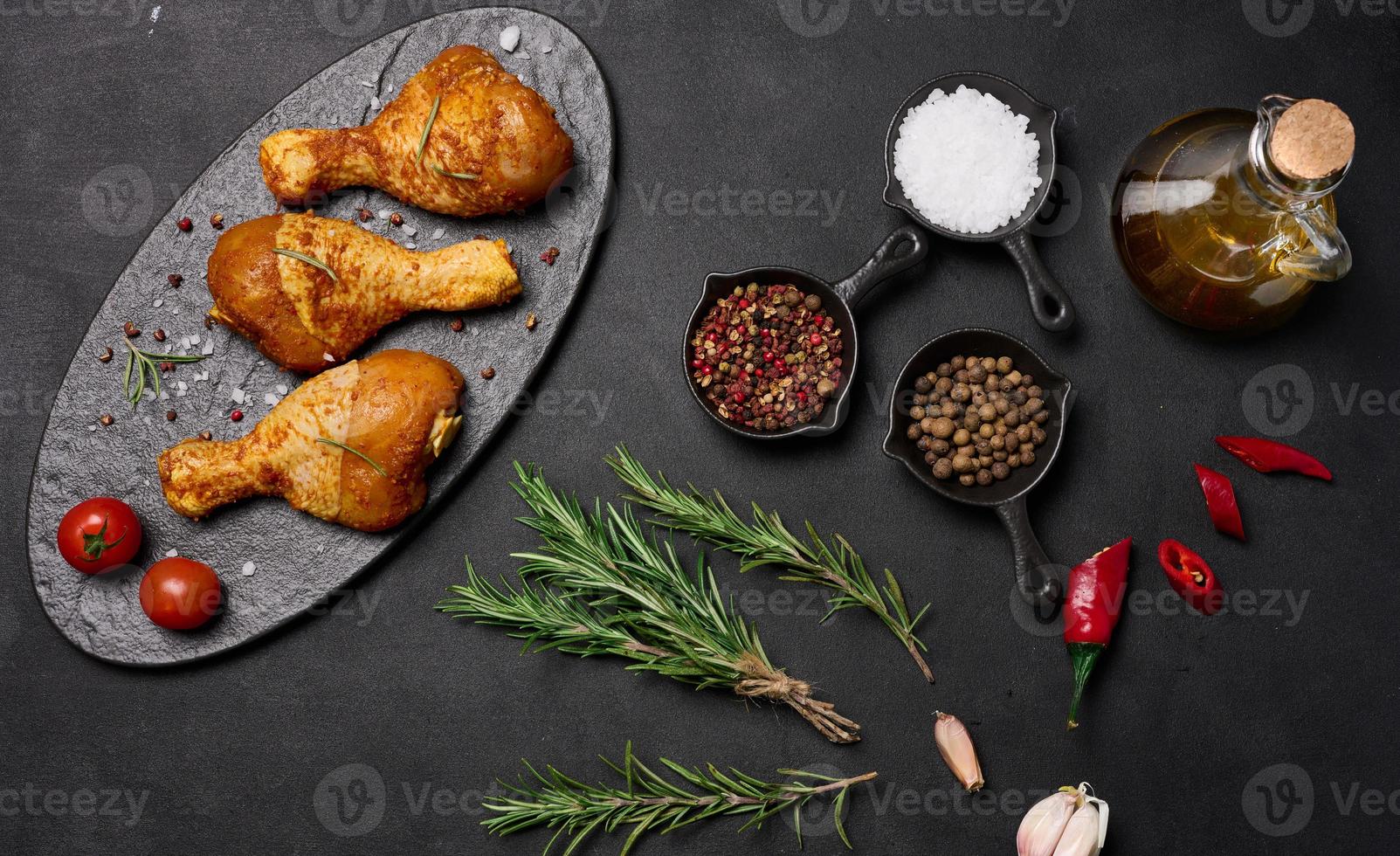 Raw chicken legs in spices on a black board, top view. Cooking with spices photo