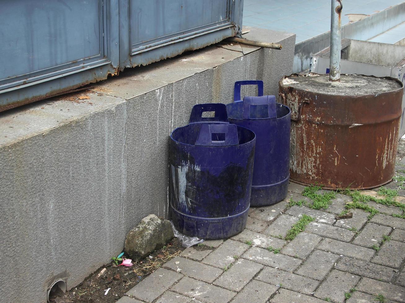 Empty two old big blue plastic bucket isolated on old and aged industrial stone walls and brick ground flooring. photo