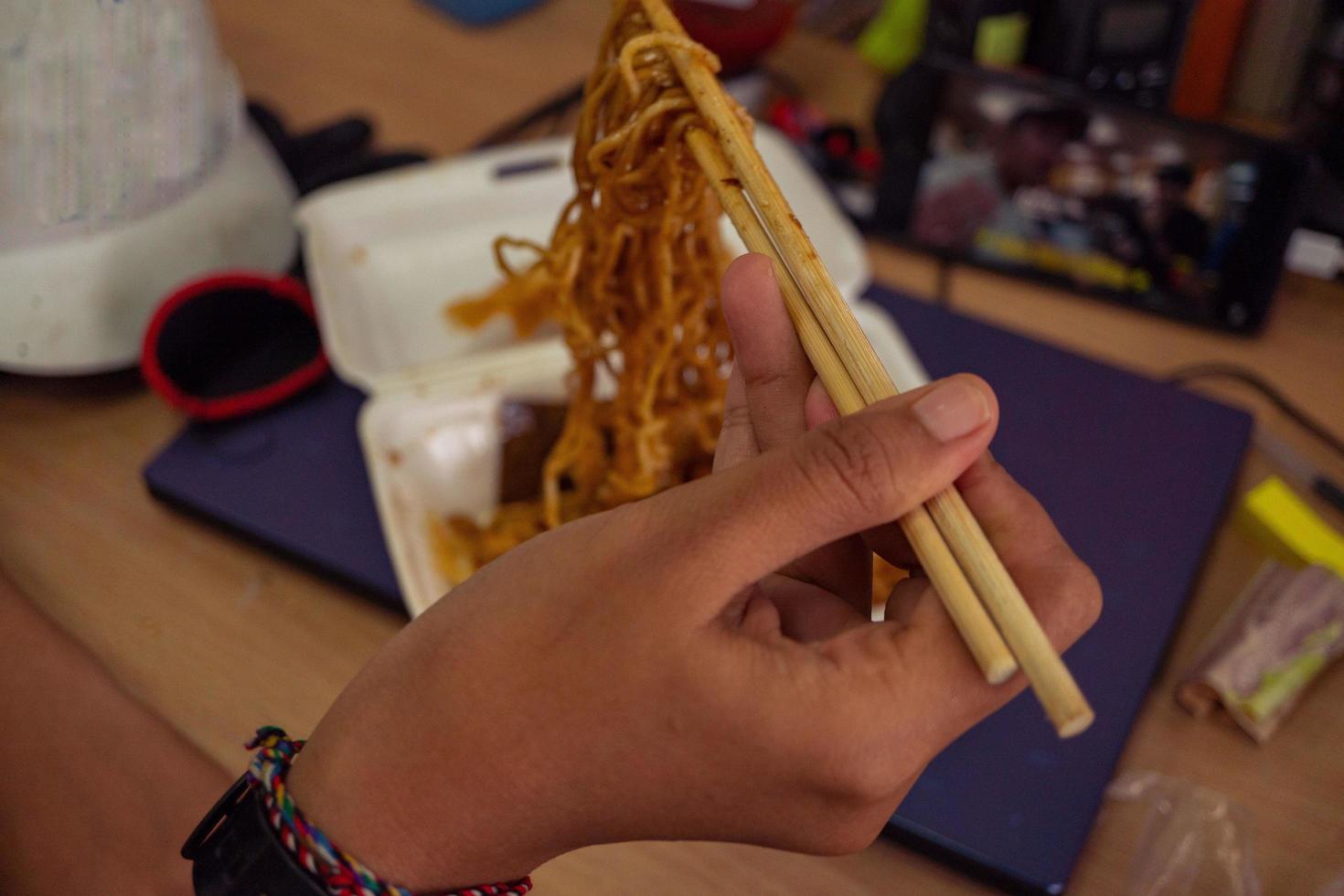 Close up photo of traditional spicy noodle from Indonesia hold with chopstick The photo is suitable to use for traditional food background, poster and food content.