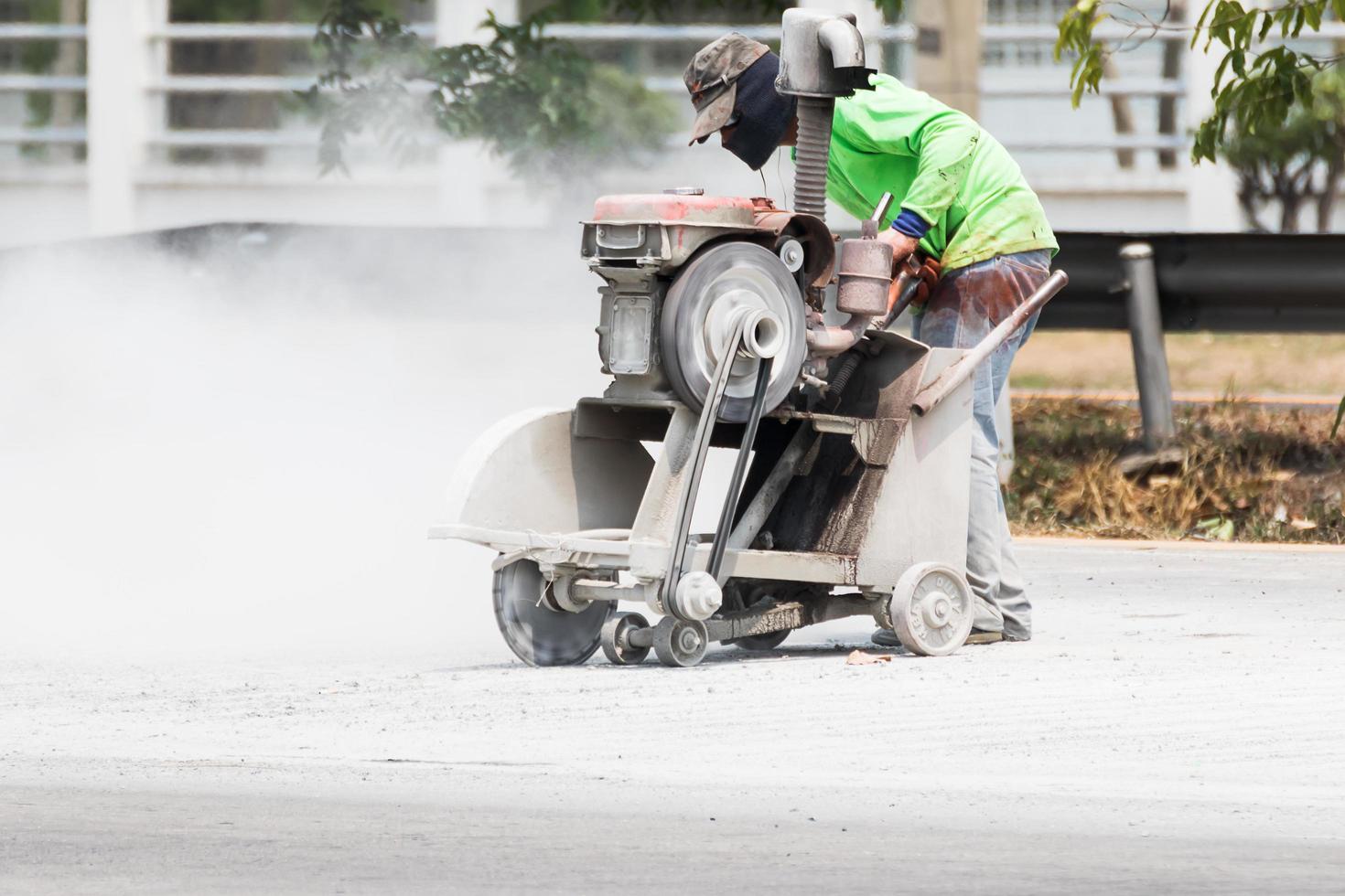 Worker cutting asphalt road photo