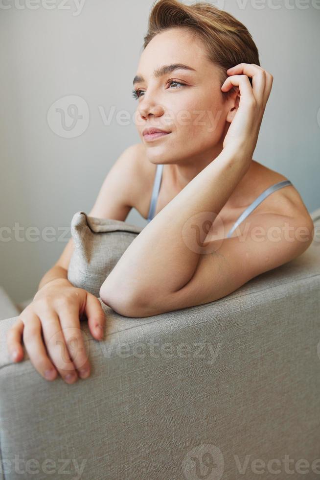 Happy woman smile lying at home on the couch relaxing on a weekend at home with a short haircut hair without filters on a white background, free copy space photo