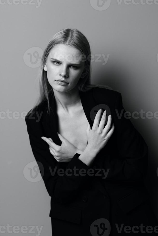 Blonde in a suit hugs herself while putting on a jacket photo
