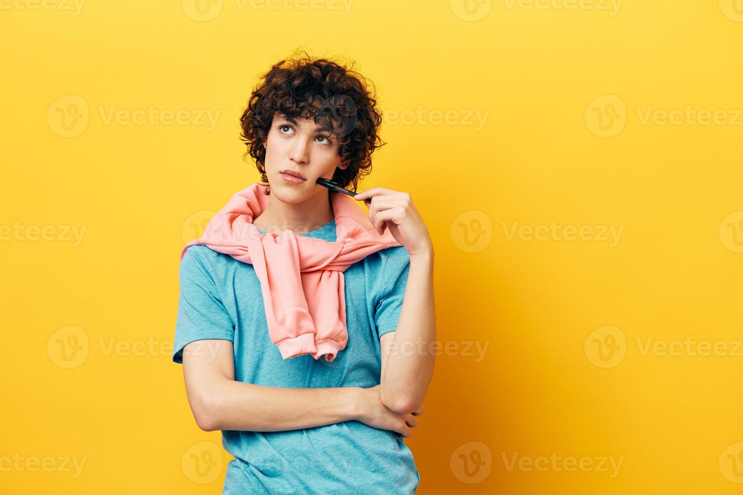 man thinks with a pen in his hands yellow background photo