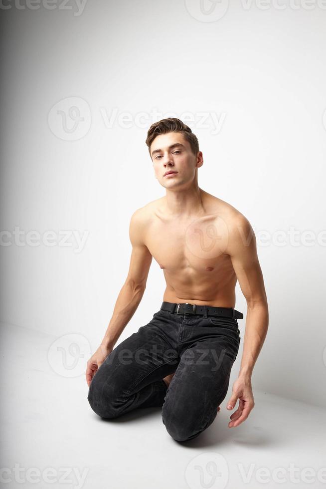 A man with a naked torso is kneeling studio posing attractive look photo
