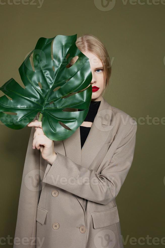 portrait of a woman in coat red lips fashion palm leaf isolated background photo