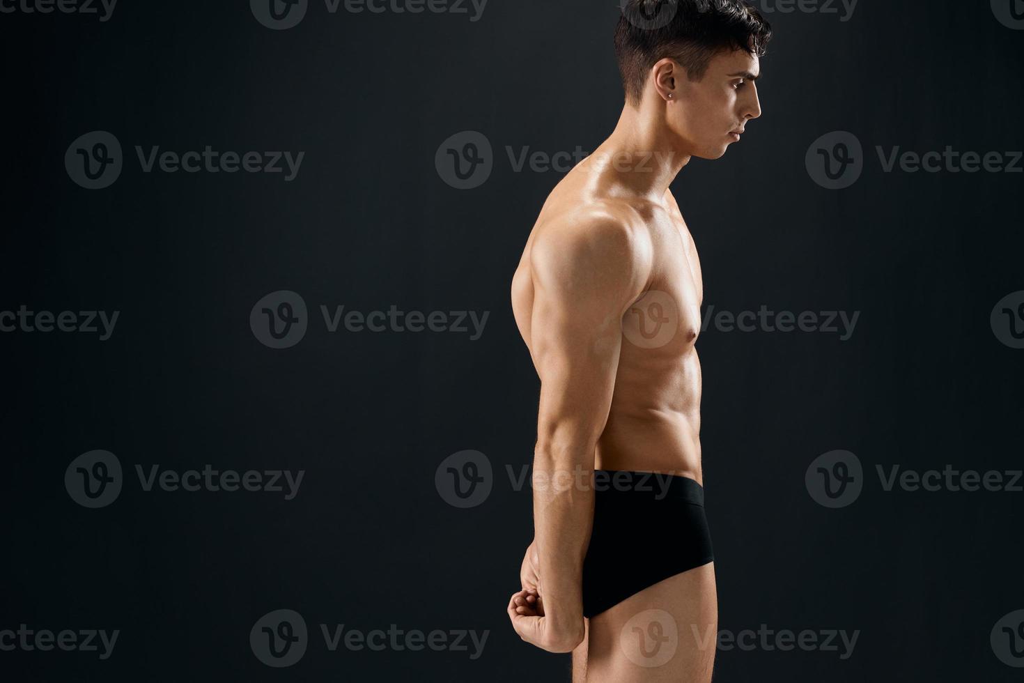 handsome man with muscular body in dark panties side view photo