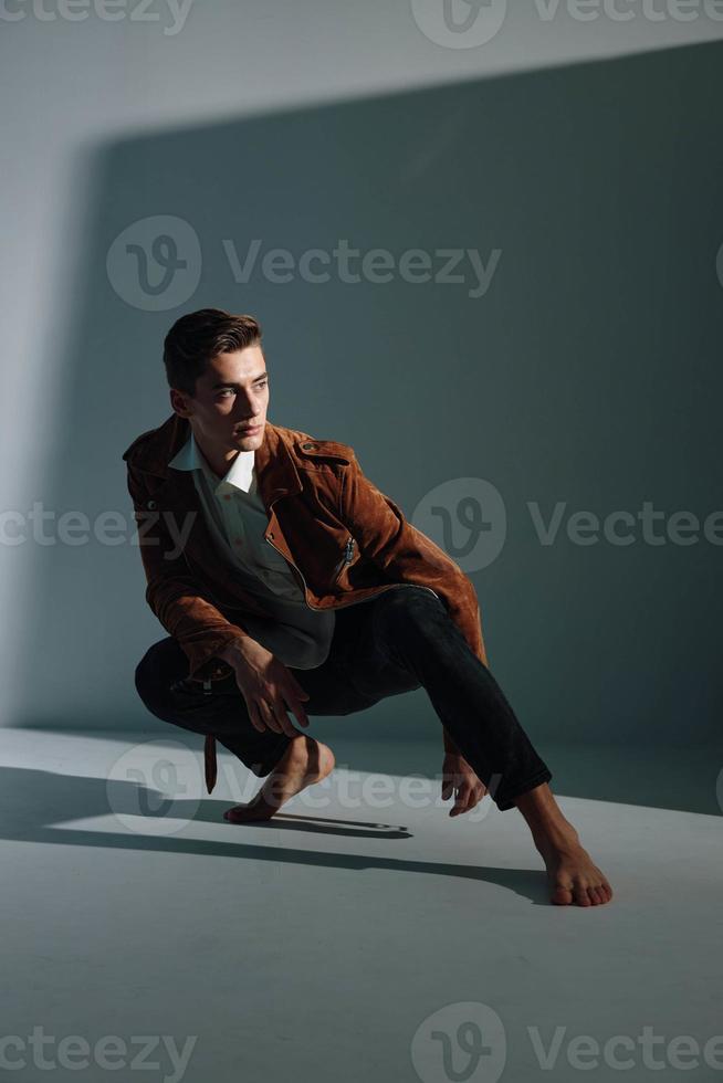 handsome guy in brown coat and jeans sneaks up and looks away photo