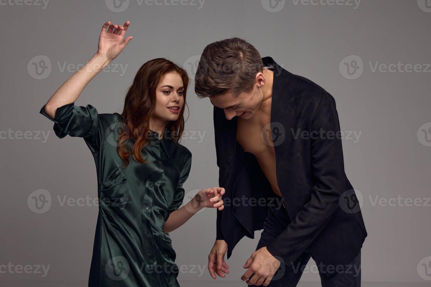 A man in a jacket on a naked torso and a woman with a raised hand photo