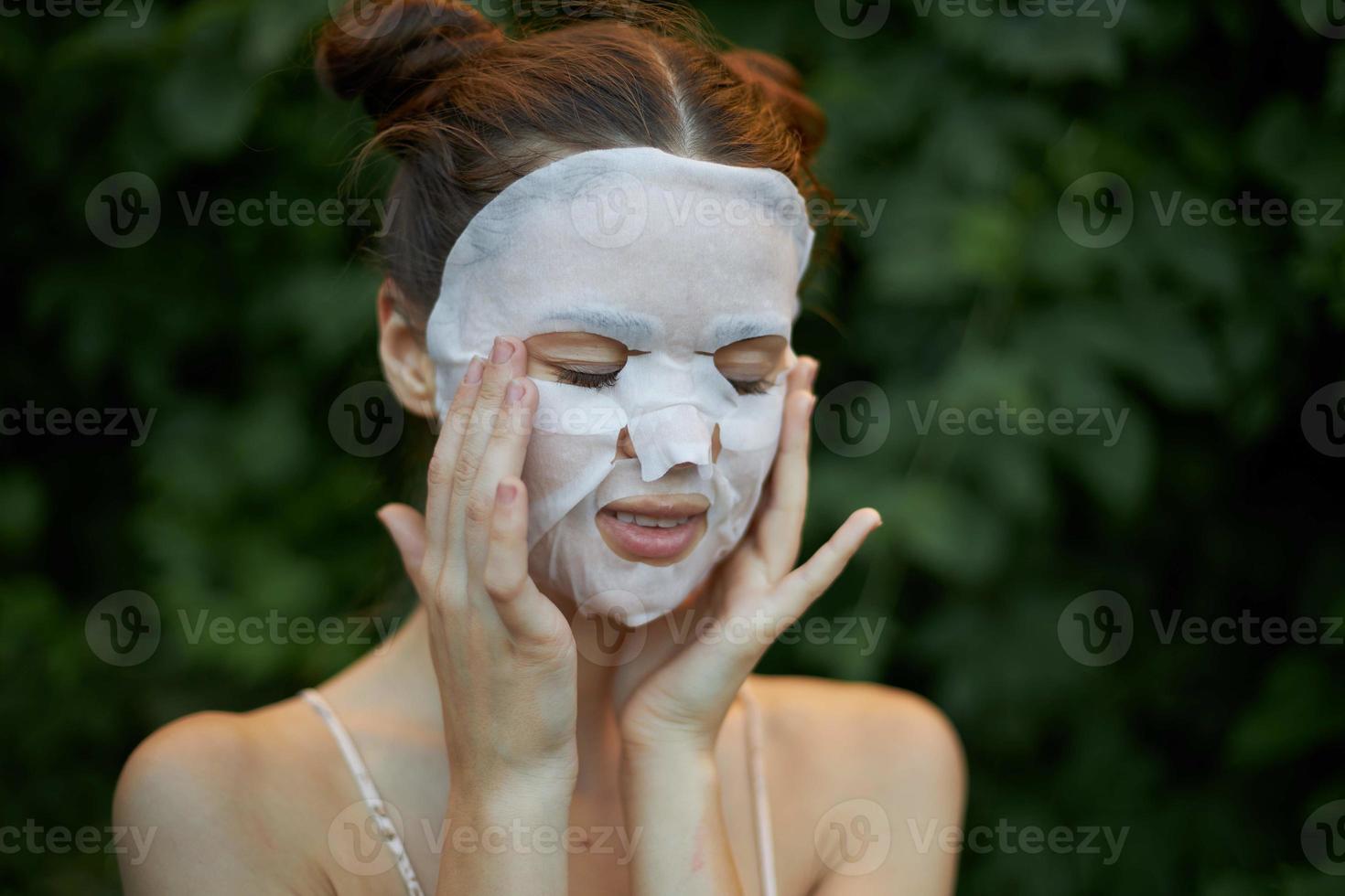 Beautiful woman With his eyes closed, touches his face with his hands white mask skin care photo