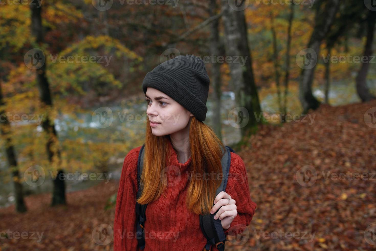 woman hiker walks in the forest in autumn in nature near the river and leaves landscape photo