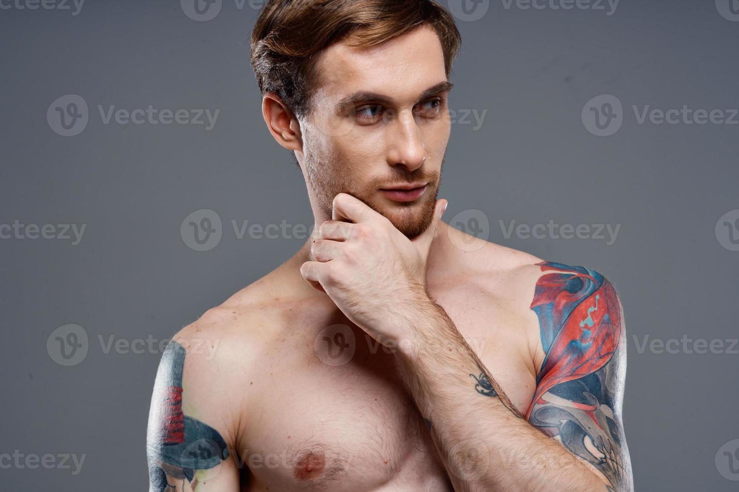 portrait of young man with tattoos on gray background and beautiful face model cropped view photo