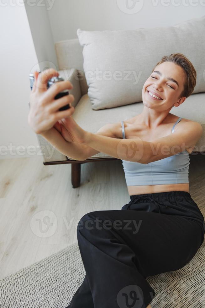 Happy smile woman holding an old camera and taking pictures of herself as a weekend photographer in home clothes with a short haircut hair without filters on a white background, free copy space photo