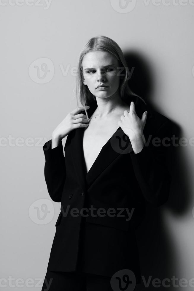 A stylish woman holds a jacket collar while posing in the studio. Fashionable stylish photo. Concept for clothing brands photo