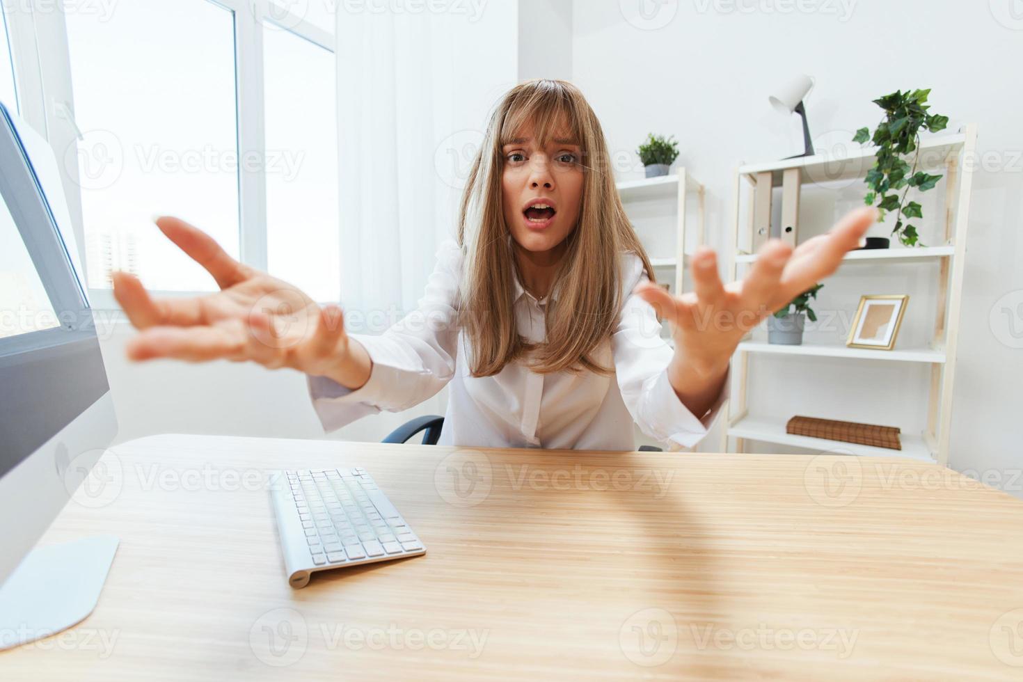 Shocked upset adorable blonde businesswoman worker freelancer made a critical mistake opening mouth thinking of problem solution spread hands at camera in light modern office. Copy space, wide angle photo