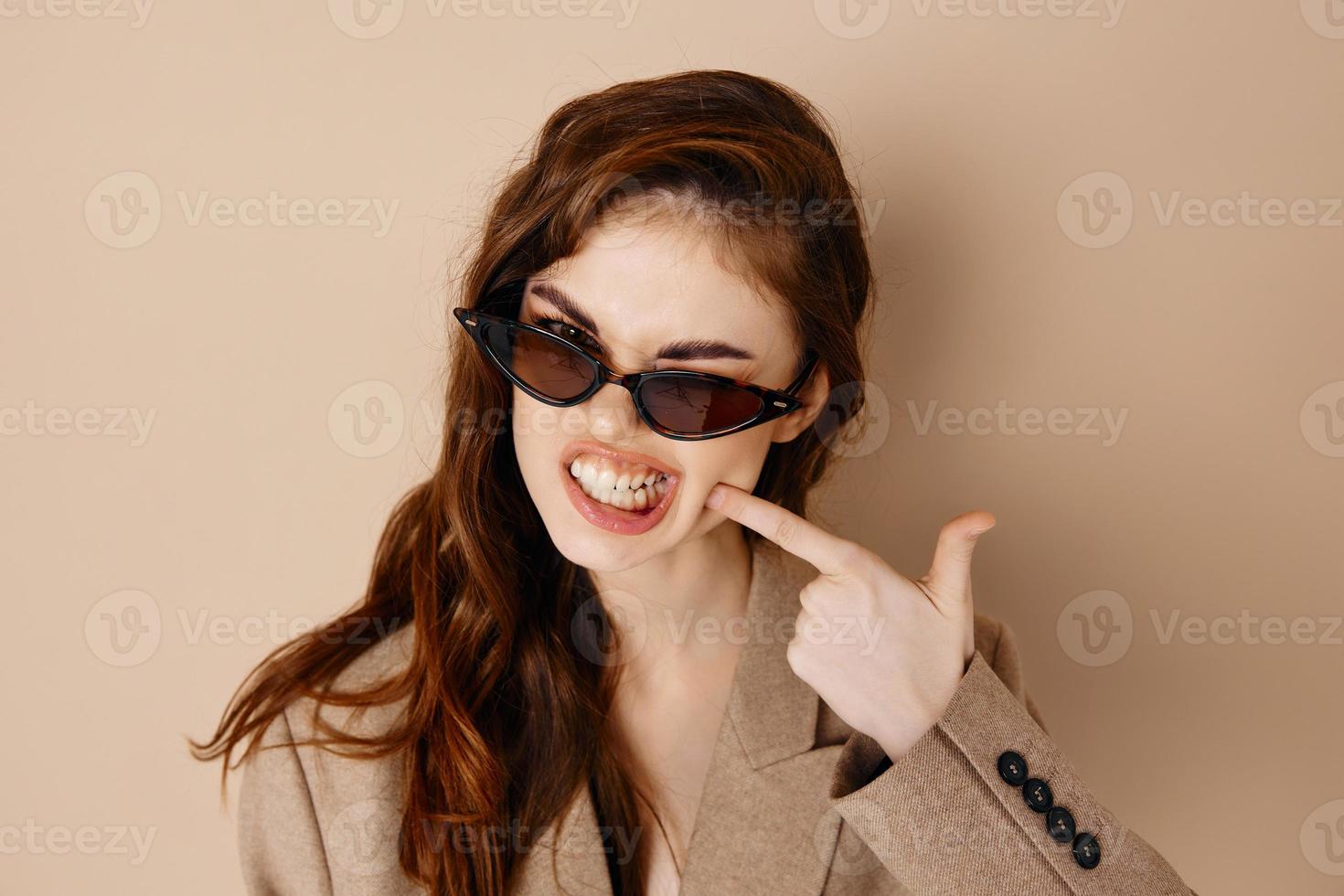 emotional woman in glasses and in a beige coat shows her finger to the side on a white background Copy Space photo
