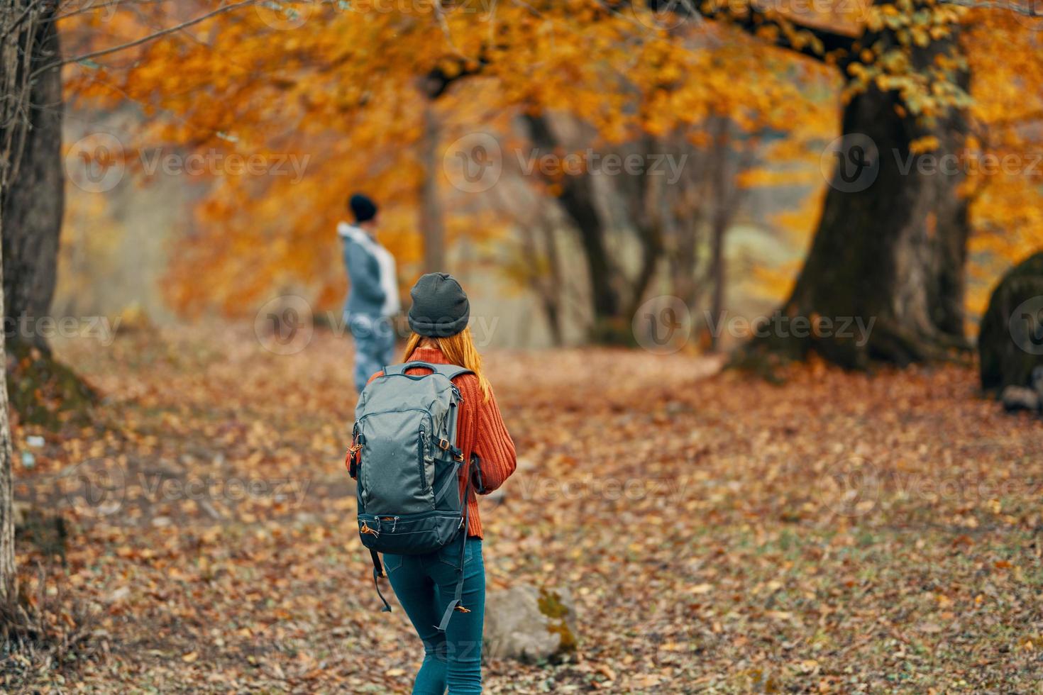 woman with a backpack are walking in the autumn forest in nature landscape trees passers-by model photo