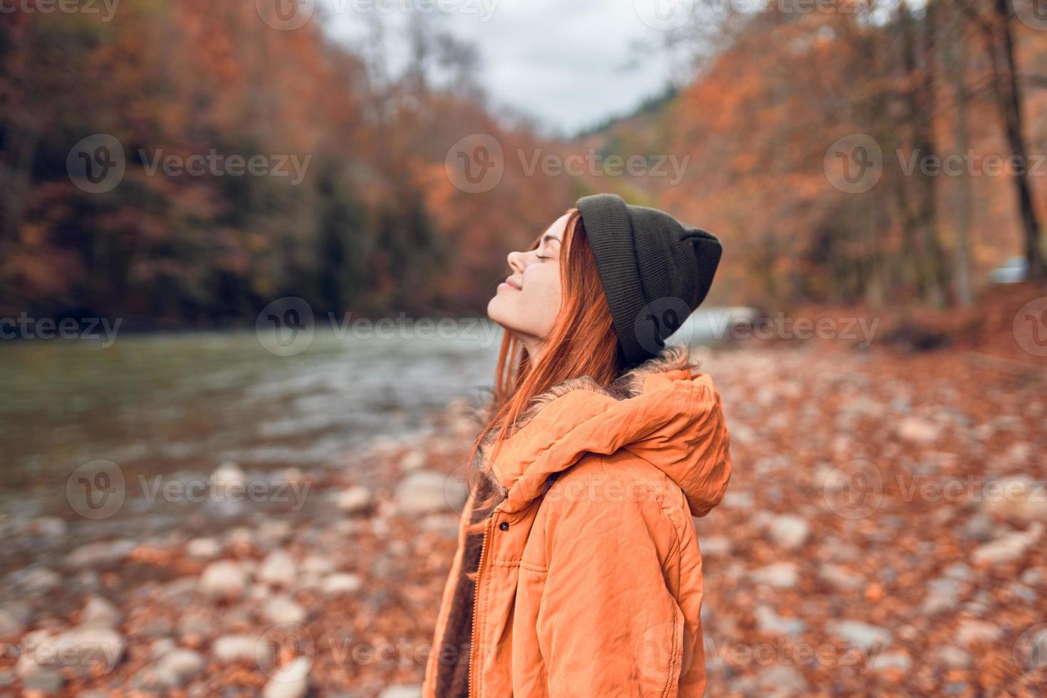 bonito mujer en otoño ropa en el bosque río caído hojas foto