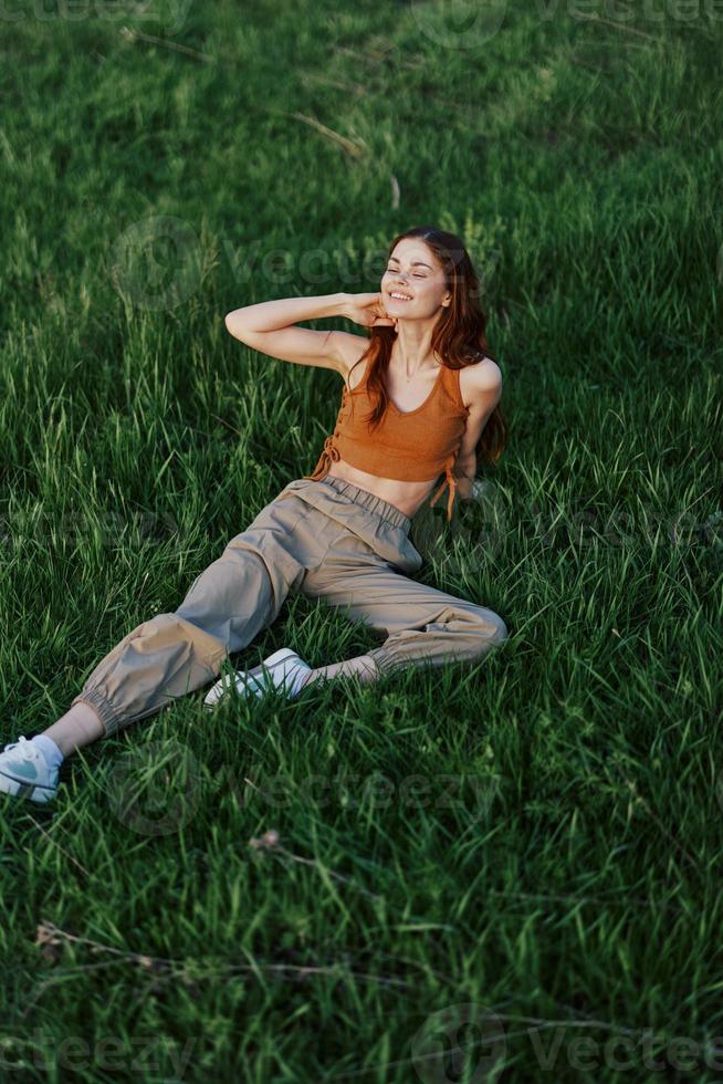 A woman lies on fresh spring green grass in a park without mosquitoes or ticks and enjoys relaxing while watching the sunset. The concept of safe outdoor recreation photo