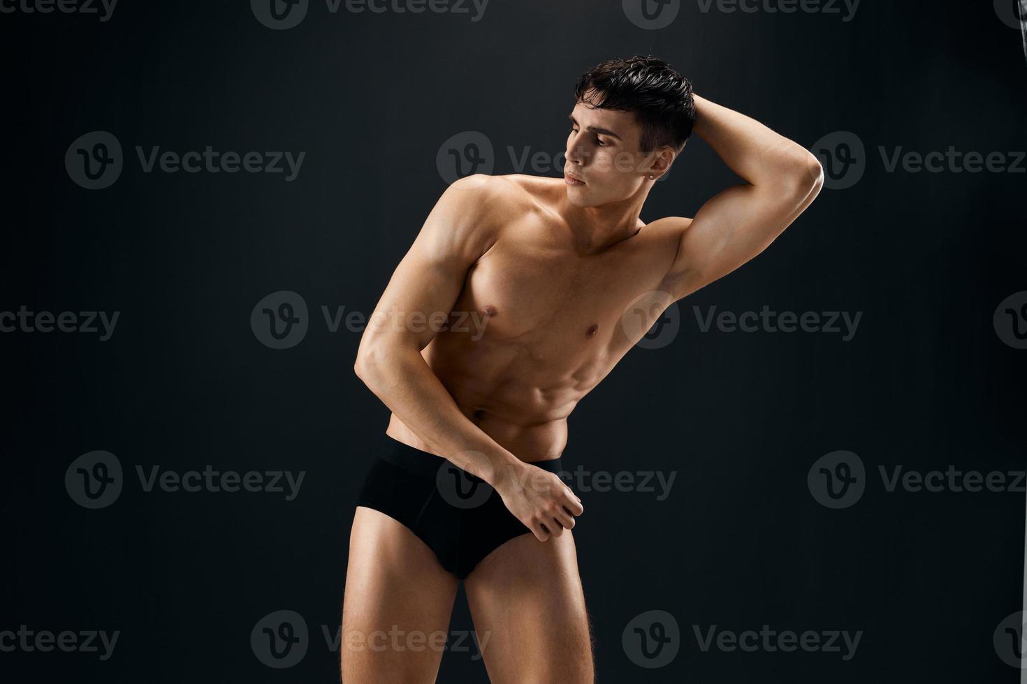 handsome residual muscular body man posing in dark isolated background photo